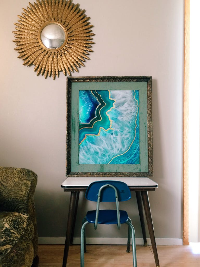 A vibrant painting on a table beneath a sunburst mirror in a cozy room.
