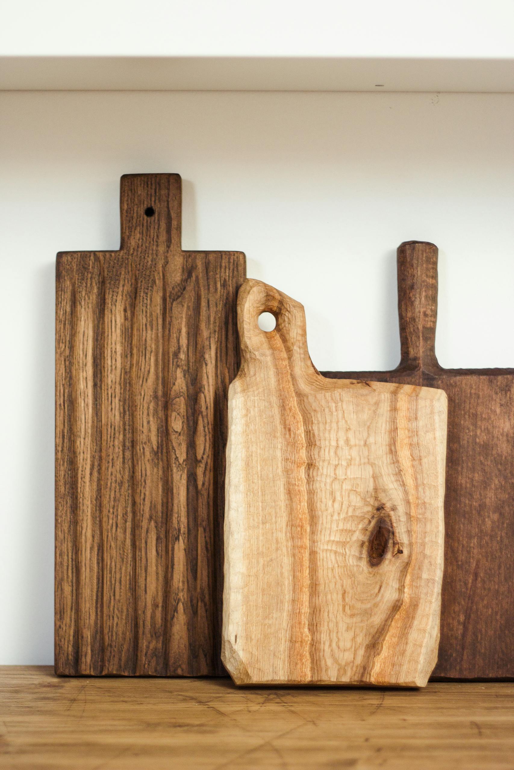 Wooden cutting boards leaning against a white wall, showcasing a minimalist and rustic kitchen vibe.